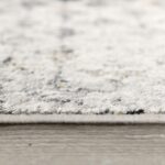 Close-up of textured gray carpet on wooden floor.