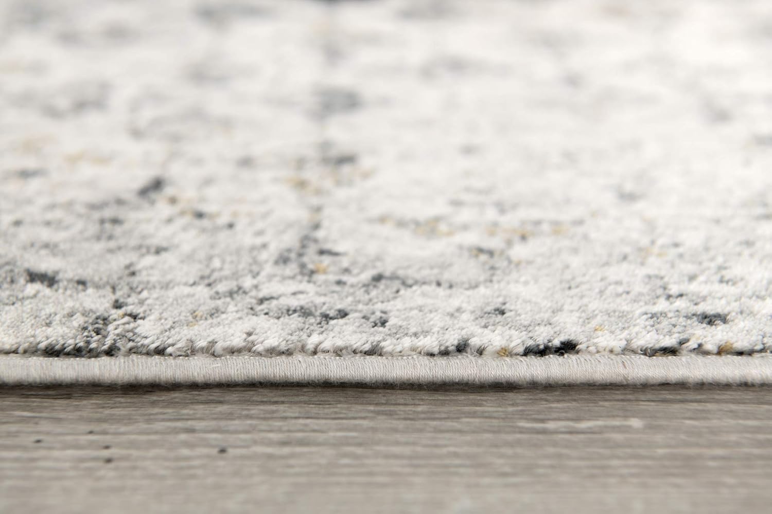Close-up of textured gray carpet on wooden floor.