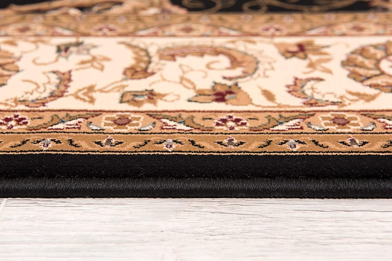 Side view of ornate beige rug on wood floor.