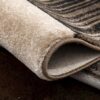 Close-up of a rolled, textured beige carpet.