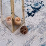 Decorative candles and sphere on patterned carpet.