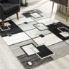 Geometric gray and black area rug on hardwood floor.