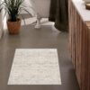 Modern bathroom with rug near tub and plants.