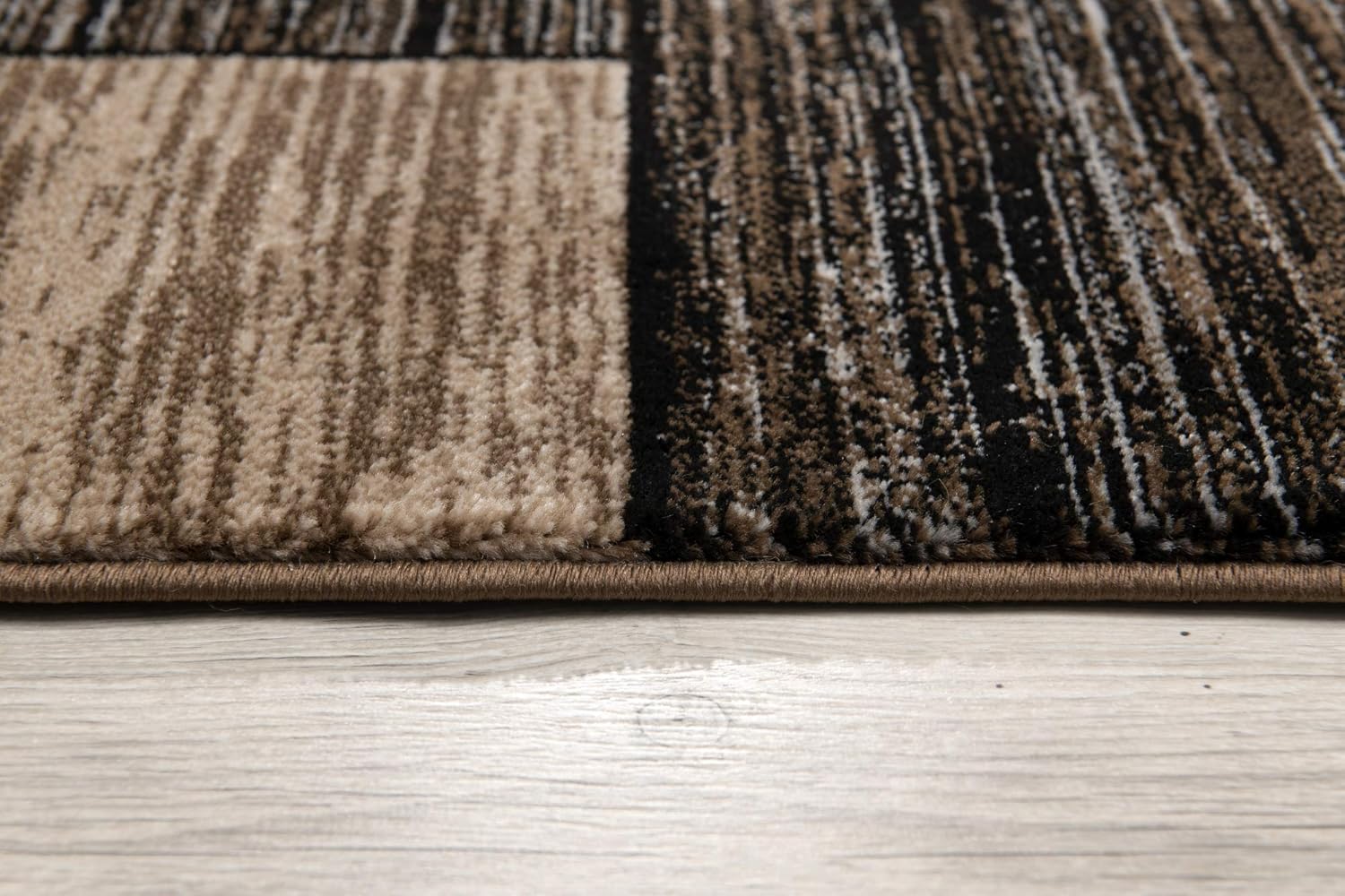 Close-up of patterned carpet edge on wooden floor.