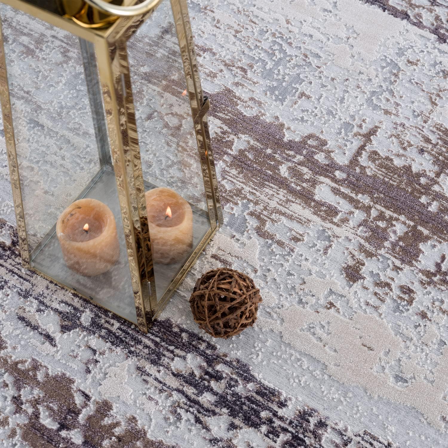 Lantern and candles on abstract patterned rug.