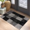 Checkered gray and black rug by a window.