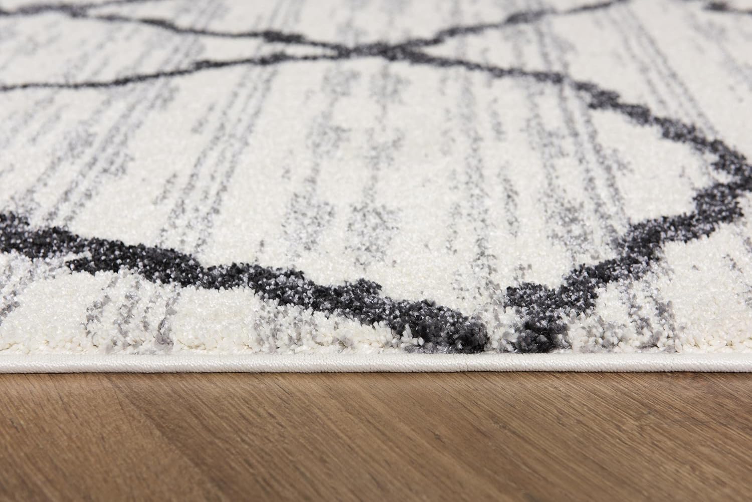 Close-up of white and gray area rug on wood floor.
