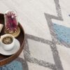 Coffee, book, and flowers on a geometric rug.