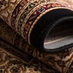 Rolled ornate patterned carpet in detail.