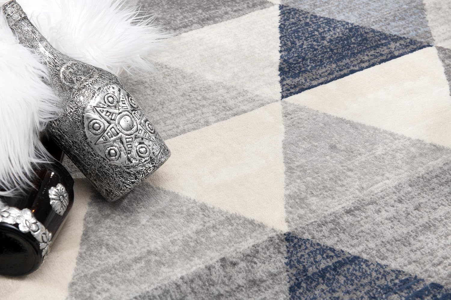 Geometric-patterned rug with decorative silver bottle.