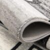 Close-up of rolled gray patterned rug.