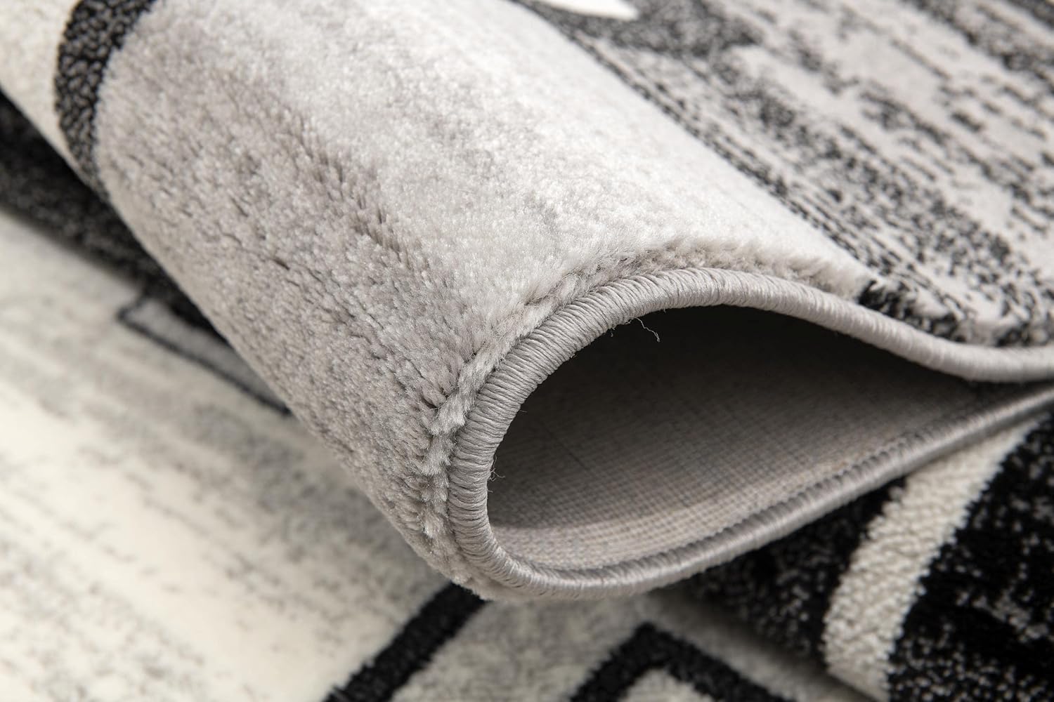 Close-up of rolled gray patterned rug.