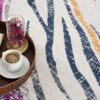 Coffee on tray with book and flowers on rug.