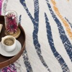 Coffee on tray with book and flowers on rug.