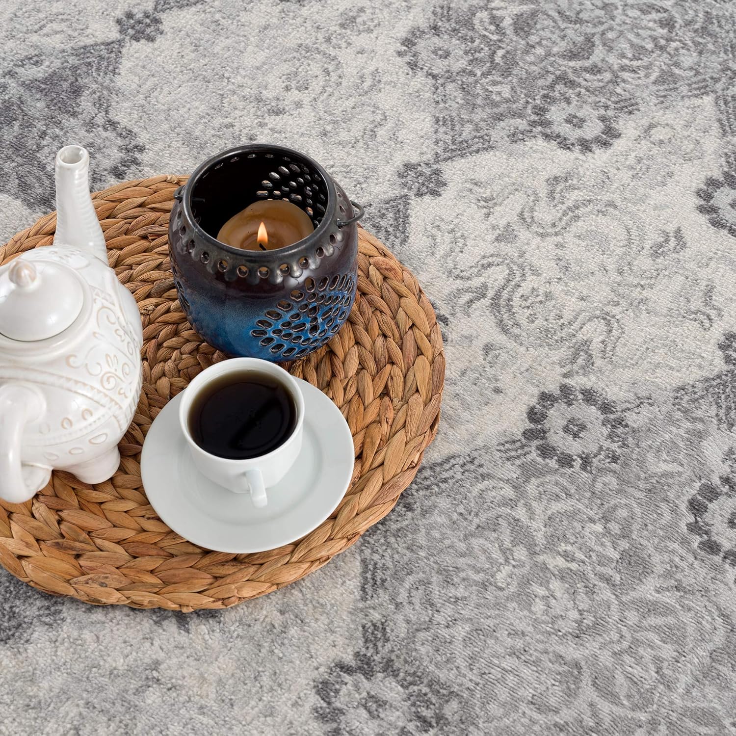 Tea set on woven placemat with candle and cup.