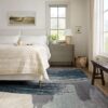 Spacious bedroom with beige bedding and window view.