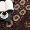 Open book and coffee on patterned carpet.