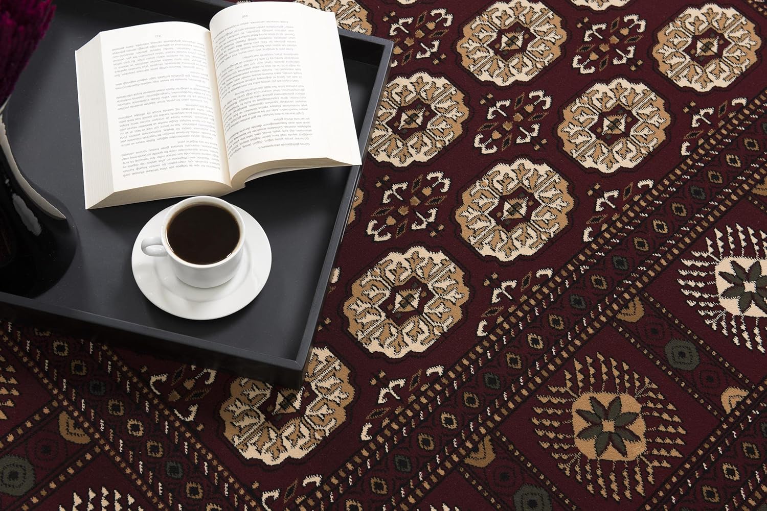 Open book and coffee on patterned carpet.
