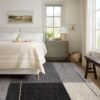 Modern bedroom with cozy decor and large window.