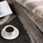 Cozy coffee on patterned rug with book and wheat.