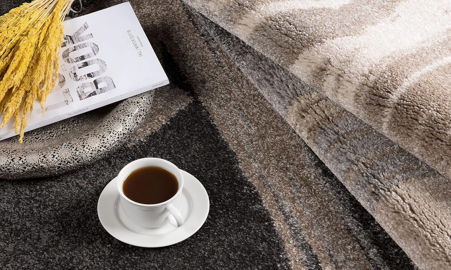 Cozy coffee on patterned rug with book and wheat.