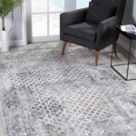 Modern living room with patterned rug and gray chair.