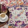 Colorful rug with coffee, book, and flowers on tray.