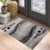 Gray geometric rug near door, wooden floor, decor items.