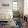 Cozy bedroom with abstract-patterned rug and large window.