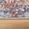 Abstract-patterned rug on wooden floor close-up.