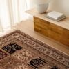 Ornate rug on wooden floor with bench and book.