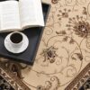 Coffee and open book on ornate rug.