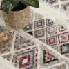 Colorful geometric rug with candle and plant decor.