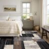 Modern bedroom with geometric rug and natural light.