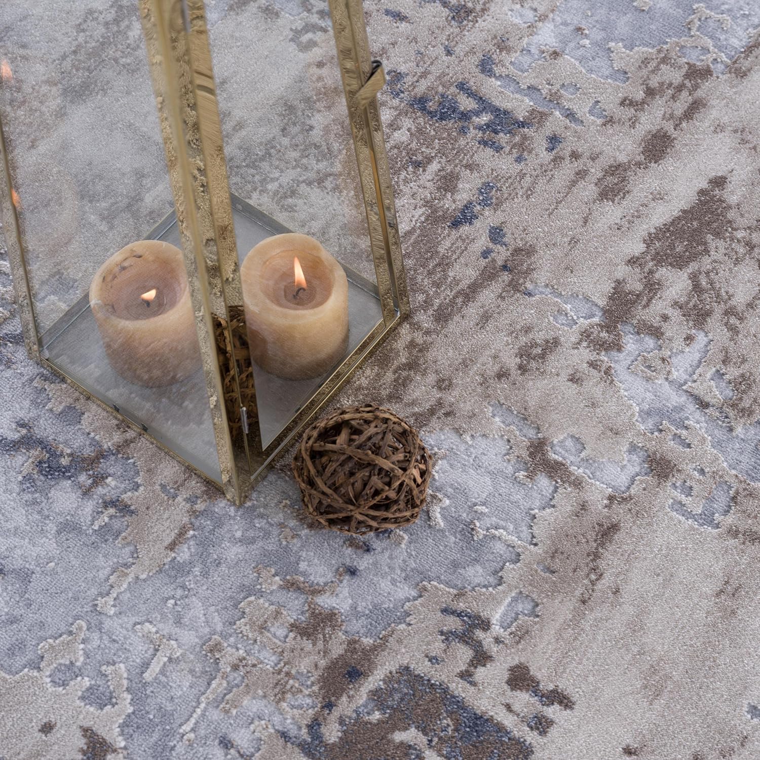 Candle lantern on patterned rug with decorative ball.