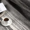 Coffee cup on gray patterned carpet with book