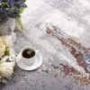 Floral arrangement with coffee on textured rug.