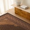 Elegant patterned rug on wooden floor near table.