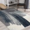 Abstract rug on wooden floor near chair.