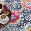 Coffee and book on colorful patterned carpet.