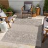 Outdoor patio with patterned rug and seating area.