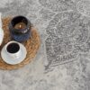 White teapot, candle, coffee on patterned rug.