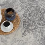 White teapot, candle, coffee on patterned rug.