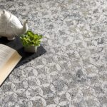 Teapot, open book, and plant on floral carpet