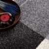 Teapot and book on gray patterned rug.