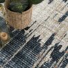 Modern abstract rug with plant and candle lantern.