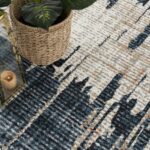 Modern abstract rug with plant and candle lantern.