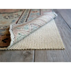 Rug pad under colorful carpet on wooden floor.