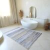Modern bathroom with freestanding tub and striped rug.