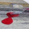 Red wine spill from overturned glass on carpet.